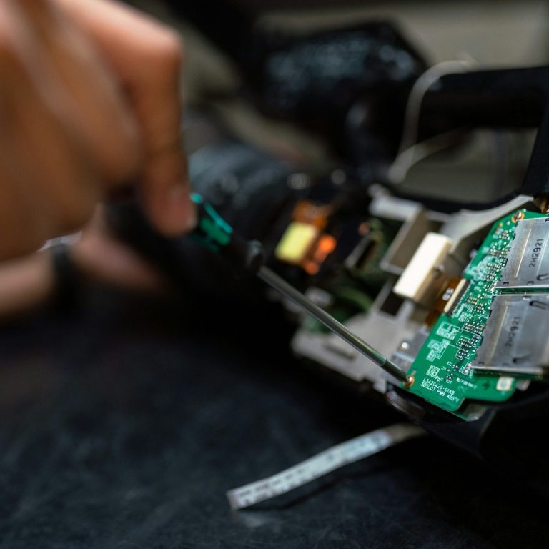 A close-up of a person repairing a circuit board inside a device.